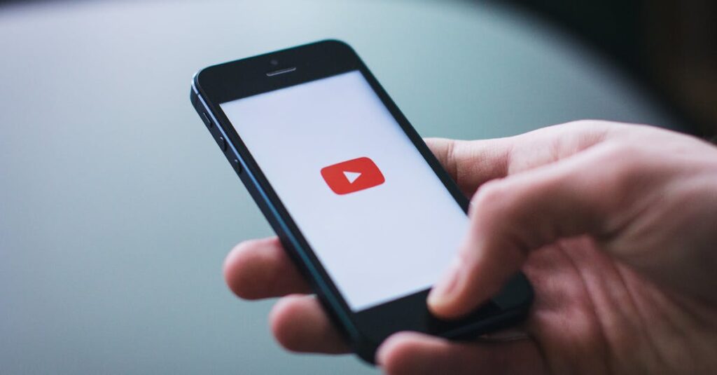 Close-up of a hand holding a smartphone displaying the YouTube app on the screen.
